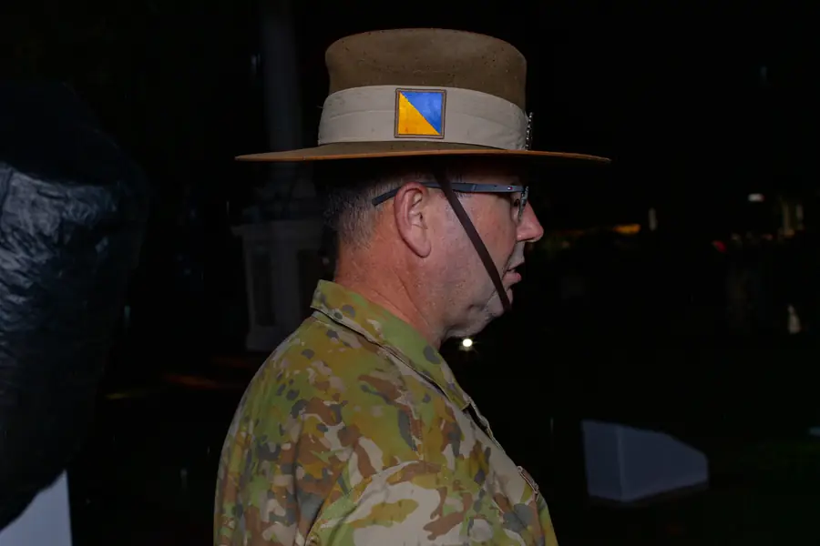 A soldier in slouch hat stands in quiet reflection at dusk.