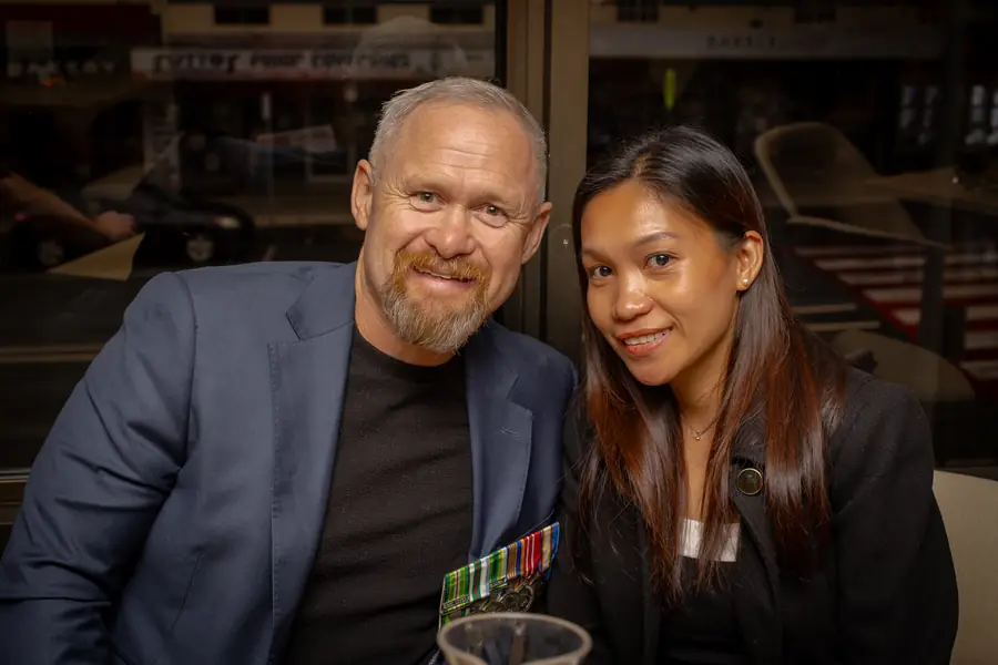 An attendee wearing service medals with a guest at the ANZAC Day event.