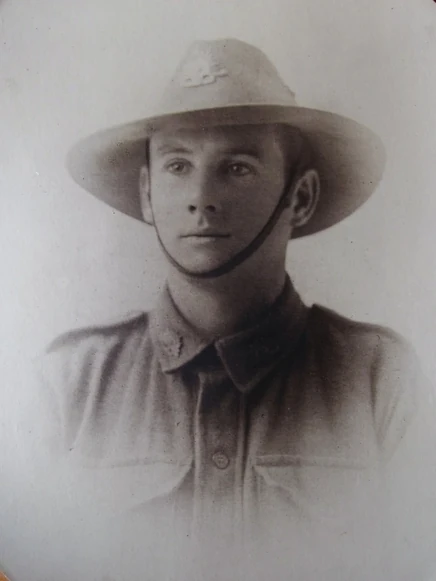 Studio portrait of Harry Comper as a young soldier, in a slouch hat bearing the Rising Sun badge, with the chin strap under his lip, and an AIF tunic.